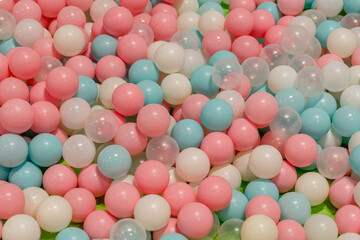 Smal plastic balls for indoor ball pit children kids playground. White blue pink colored background