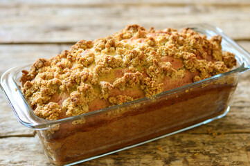 Cake (pie) decorated with streusel. Cake in a glass baking dish. Wooden background.