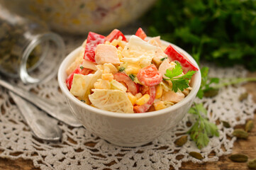 Beijing cabbage and sweet pepper salad in a white plate. Wooden background.