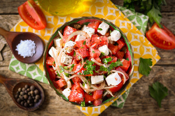 Salad with tomatoes, onions and mozzarella, garnished with herbs. Wooden background.