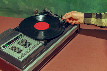 Image of old-fashioned vintage vinyl record player isolated over dark green background