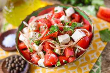 Salad with tomatoes, onions and mozzarella, garnished with herbs. Wooden background.