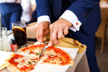 Man in suit eating pizza while standing