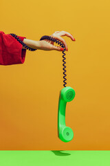 Colorful bright image of female hand holding old-fashioned green colored phone, handset isolated...
