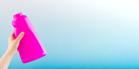 Lady holds purple bottle of liquid detergent on light blue background closeup