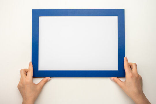 Holding frame mockup. Photo Mockup. Woman hands hold blue frame. For frames and posters design. Frame size A4. blank photo frame border with copy space in hands close up