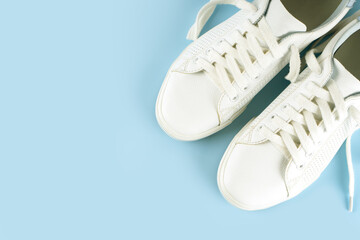 Pair of white sneakers on blue background. Unisex shoes, stylish white sneakers. Top view, flat lay, mockup with copy space for text