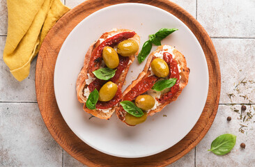 Bruschetta with sun dried tomatoes. Toast or sandwich with ricotta, sun dried tomatoes and Provence herbs with basil servered on a plate on a grey old cracked tile table. Top view banner menu recipe.