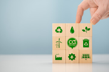 Climate neutral long term strategy. Hand put wooden cubes with green icon and green icon on blue background. Carbon neutral sustainable development concept. Green industry.