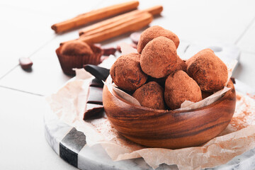 Chocolate truffles with cocoa powder in wooden dish on old cracked tile table background. Tasty sweet chocolate truffles candies. Valentine's Day and Mother's Day concept with copy space. Top view.