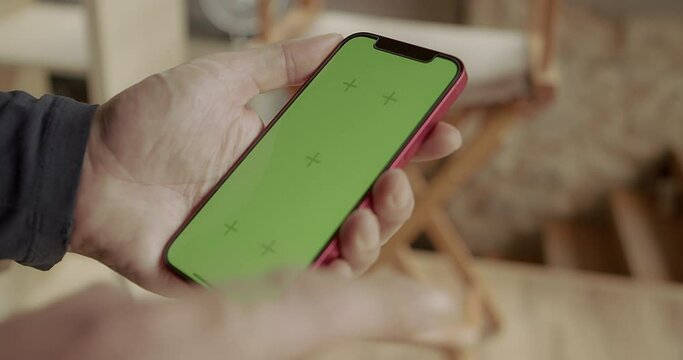 A man's hand swipes his finger across the touch screen of a mobile phone. Mockup. Green screen. Copy space