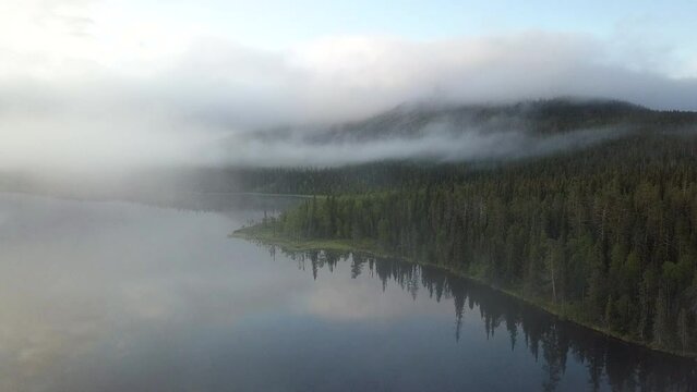 Aerial view of lake and forest filled with mist in Lapland Finland
