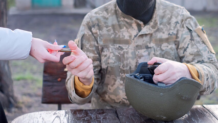 Hand of unidentified woman passes ammunition to a Ukrainian soldier in camouflage shirt for loading...