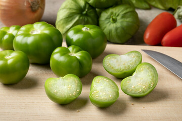 Fresh green whole and halved tomatillo on a cutting board close up