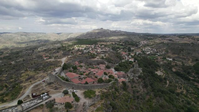 Drone aerial panoramic view of Sortelha historic village and wind turbines in natural landscape, Portugal