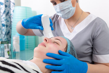 Obraz premium Young woman receiving electric galvanic anti-aging face spa massage at beauty salon.