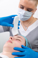 Young woman receiving electric galvanic anti-aging face spa massage at beauty salon.