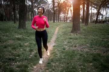 Young athletic sporty girl training in green forest during summer autumn season on forest path. 