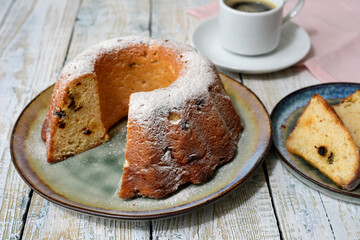 Traditional round cake with raisins, powdered sugar, on a white wooden table. Selective focus.