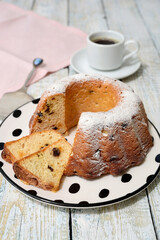 Traditional round cake with raisins, powdered sugar, on a white wooden table. Selective focus.