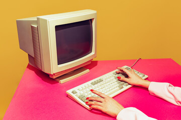 Kleurrijk beeld van vintage computermonitor en toetsenbord op helder roze tafelkleed op gele achtergrond. Informatie typen