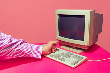 Colorful image of vintage computer monitor and keyboard isolated over bright pink background