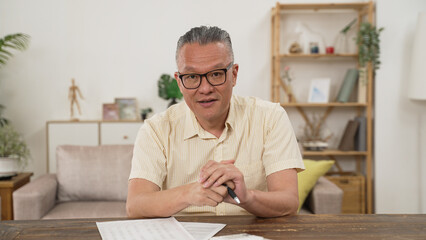 Smiling old businessman sit at the desk talking on a webcam having a video call or conversation with a client, motivated elder male coach or trainer speak shoot online tutorial, record training course