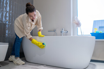 A woman doing cleaning at home and disinfecting the bathroom