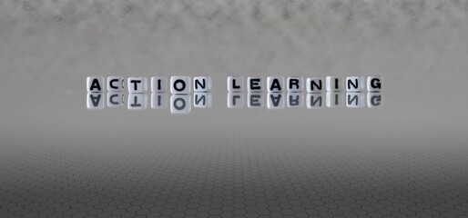 action learning word or concept represented by black and white letter cubes on a grey horizon background stretching to infinity