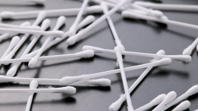 pile of q-tips or cottom buds slowly rotating on black background, loopable