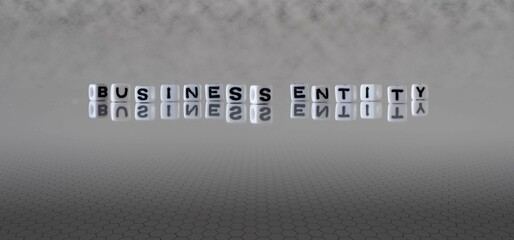 business entity word or concept represented by black and white letter cubes on a grey horizon background stretching to infinity