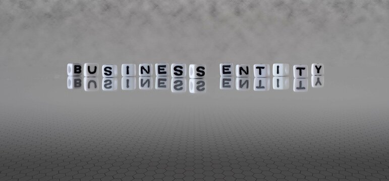 business entity word or concept represented by black and white letter cubes on a grey horizon background stretching to infinity
