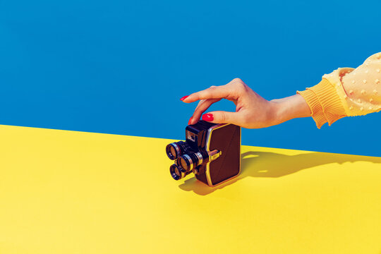 Pop art photography. Colorful image of retro photo camera on bright yellow tablecloth isolated over blue background