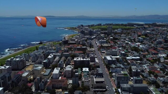 Drone shot of Sea Point, Cape Town - drone is reversing, watching paragliders coming down from Signal Hill. Snippet could ideally be used for travel related videos or Cape Town movies.