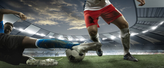 Close-up legs of soccer, football players in action, motion at the stadium with flashlights and crowded stands. Concept of sport, competition, movement, overcoming.