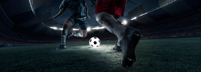 Cropped image of two soccer, football players in motion, action at stadium during football match in evening. Concept of sport, competition, goals