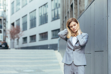 Fototapeta premium Woman near the office has severe back and neck pain, fatigue and depression of a business woman from the outside