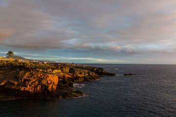 Panoramic view of the Illuminated Las Americas at night against the colorful sunset sky with lights on the horizon on Tenerife island, Spain