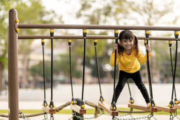 summer, childhood, leisure and people concept - happy little girl on children playground climbing...