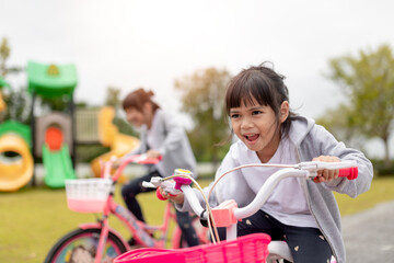Obraz premium happy cheerful child girl riding a bike in Park in the nature