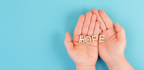 Holding the word hope in the palm of the hands, trust and believe concept, having faith in the...