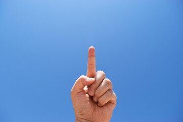 人差し指を立てる女性（青空の背景）