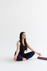Fototapeta premium Young beautiful woman practicing yoga on a white background. Young beautiful girl doing exercises at home. Harmony, balance, meditation, relaxation, healthy lifestyle concept 