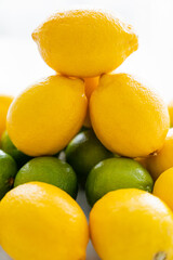 Close up view of lemons on limes with light on white background