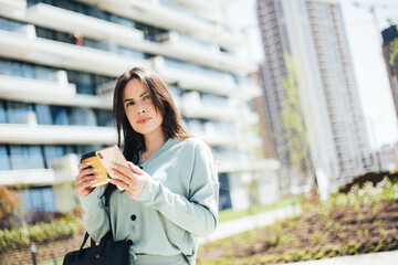 Fototapeta premium Serious confident female entrepreneur dressed in stylish suit using mobile phone while standing on street