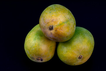 Mangoes isolated in white background, shot using studio lighting and water drops on the subject, Composition on a wooden log with extendable white background and ample copy space, Alphonso  Badami.