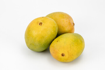 Mangoes Badami / Alphonso isolated in white background, shot using studio lighting and water drops on the subject, Composition on a wooden log with extendable white background and ample copy space.