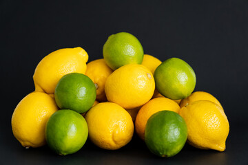 Fresh limes near lemons on black background