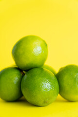 Close up view of ripe limes on yellow surface