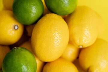 Close up view of ripe lemons and limes on yellow surface